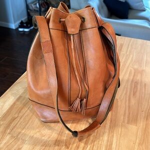 Genuine leather cognac colored bucket shoulder bag with cinch close.
